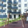 Single Swing (BNS 90cm) schommel met ronde zitting en houten frame op speelplaats.