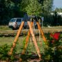 Single Swing (BNS 90cm) houten schommel met zwart zittje en metalen kettingen in speeltuinomgeving.