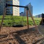 Single Swing (BNS 90cm) schommel met ronde zitting en houten frame op een speeltuin.