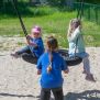 Single Swing (BNS 90cm) schommel met twee kinderen spelend op een zandondergrond.