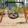 Single Swing (BNS 90cm) met een ronde netzitting en houten frame op een zandige speeltuin.