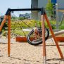 Single Swing (BNS 90cm) schommel met houten frame en zwart netzitje op een zandondergrond.